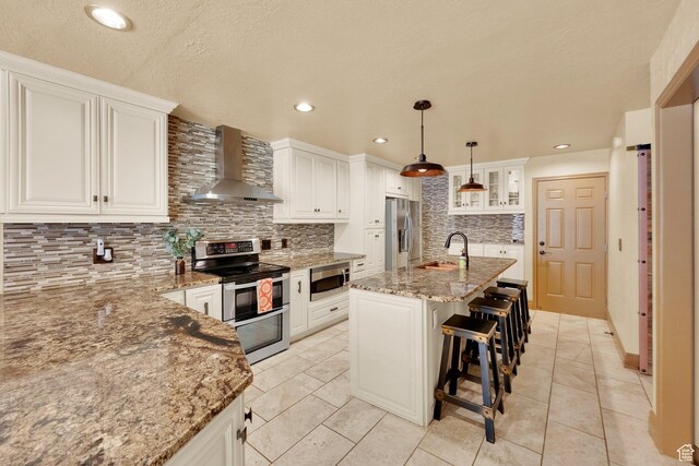 8135 S Clover Spring Ln E, Cottonwood Heights, UT 84121 - kitchen featuring wall chimney exhaust hood, stainless steel appliances, a sink, tasteful backsplash, and light stone counters
