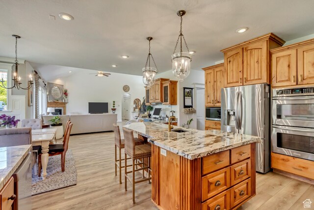 kitchen featuring stainless steel appliances, a chandelier, a sink, ceiling fan, and open floor plan