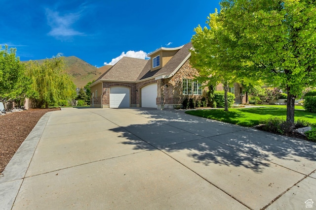traditional home featuring an attached garage, stone siding, a front yard, driveway, and brick siding