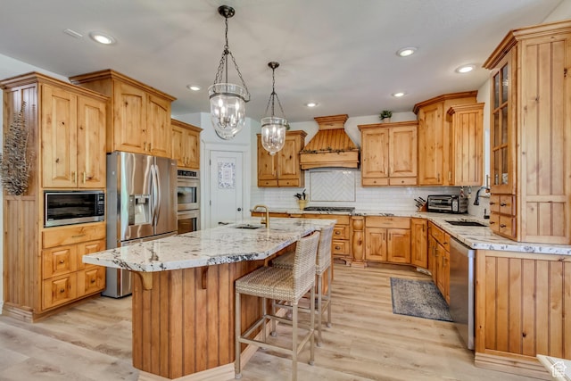 kitchen with stainless steel appliances, a sink, custom exhaust hood, light wood-style flooring, and recessed lighting