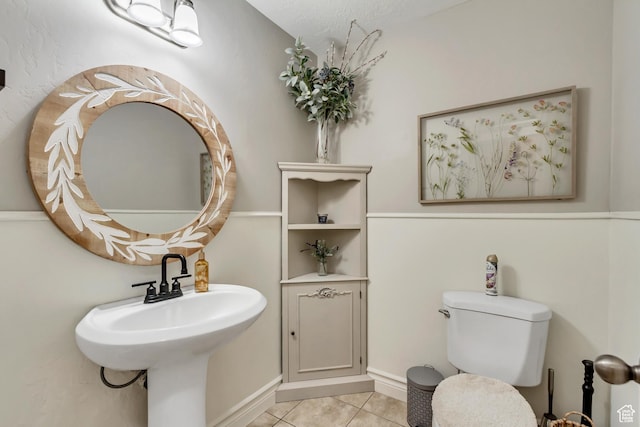 half bath with tile patterned flooring and toilet