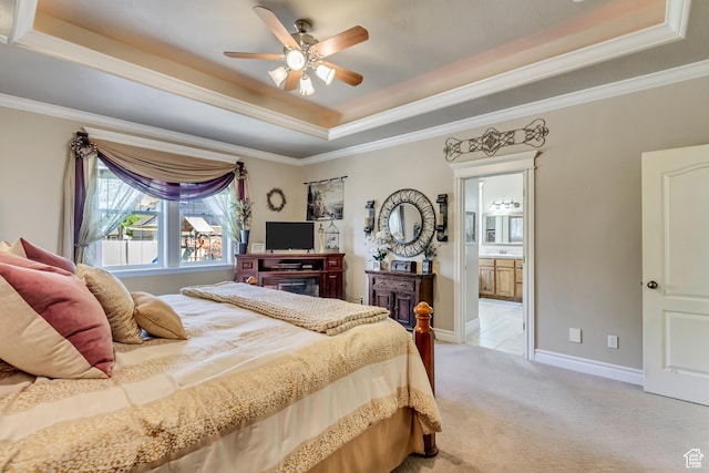 bedroom featuring a raised ceiling, light carpet, ornamental molding, connected bathroom, and a ceiling fan