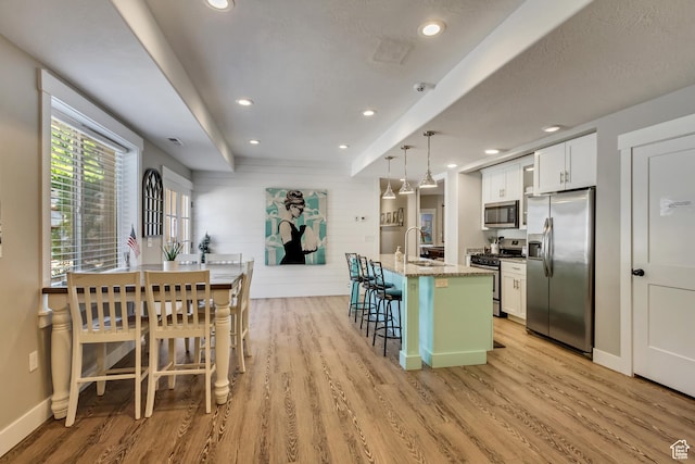 kitchen with stainless steel appliances, light wood-style floors, a kitchen breakfast bar, white cabinetry, and recessed lighting