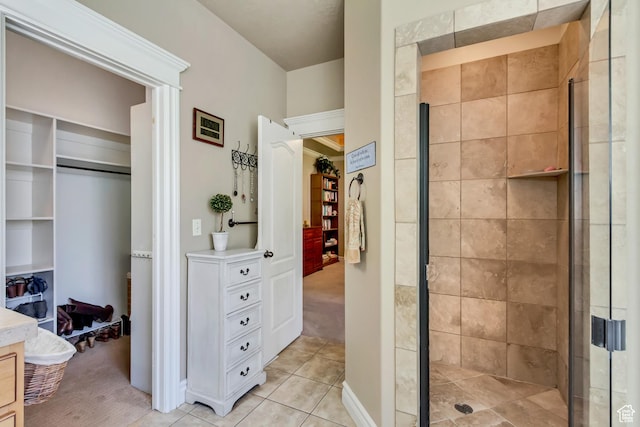bathroom with a shower stall, tile patterned floors, a walk in closet, and vanity