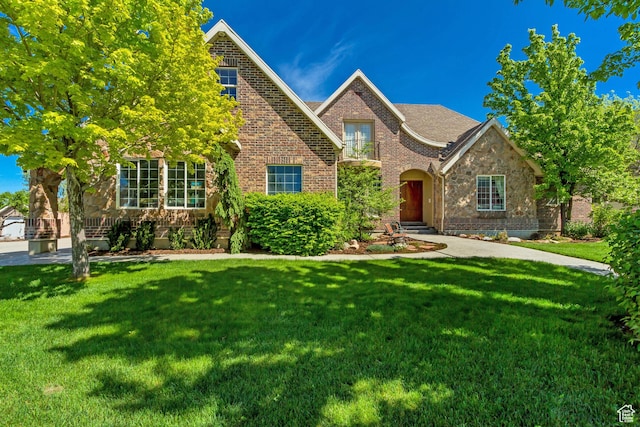 view of front facade with brick siding, a front yard, and stone siding