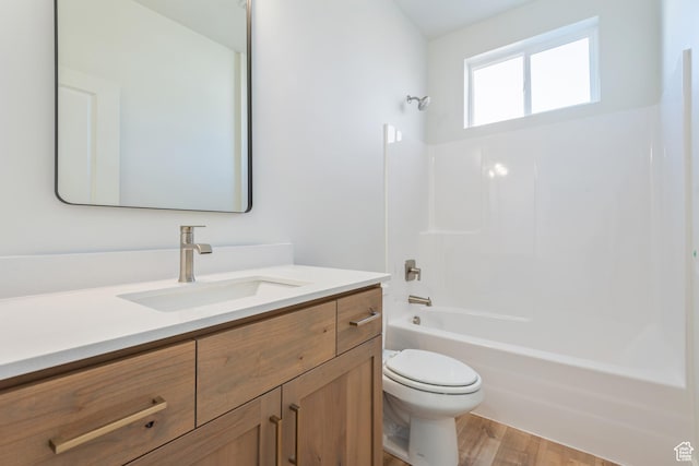 bathroom with toilet, vanity, wood finished floors, and shower / bathtub combination