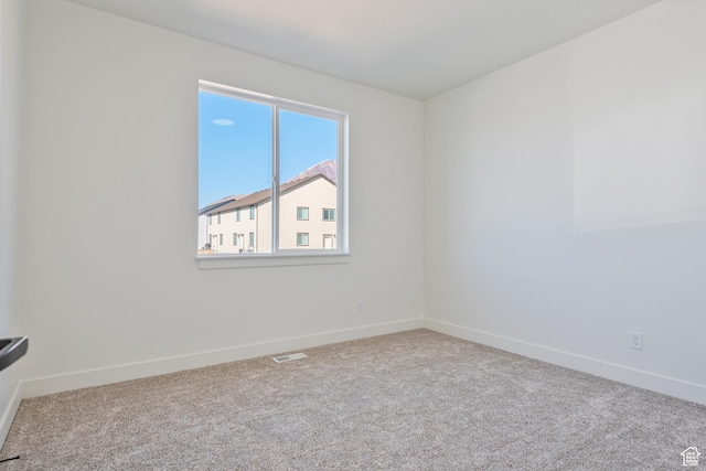 spare room featuring carpet floors and baseboards