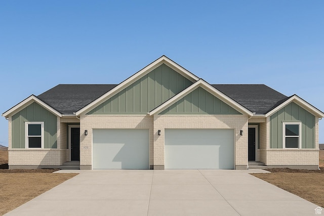 view of front facade featuring board and batten siding, driveway, brick siding, and a garage
