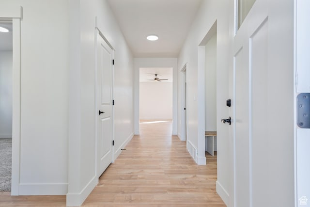 corridor featuring light wood-type flooring and baseboards