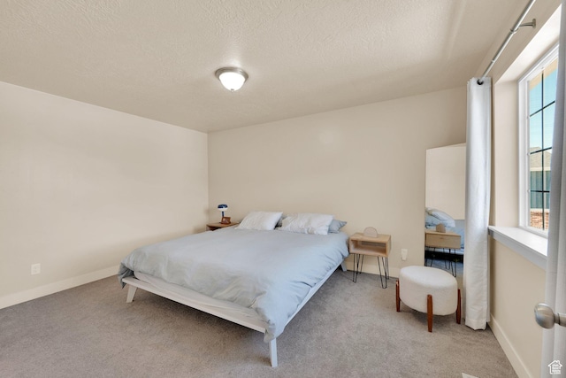 bedroom featuring multiple windows, a textured ceiling, carpet floors, and baseboards