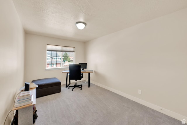 carpeted home office featuring baseboards and a textured ceiling