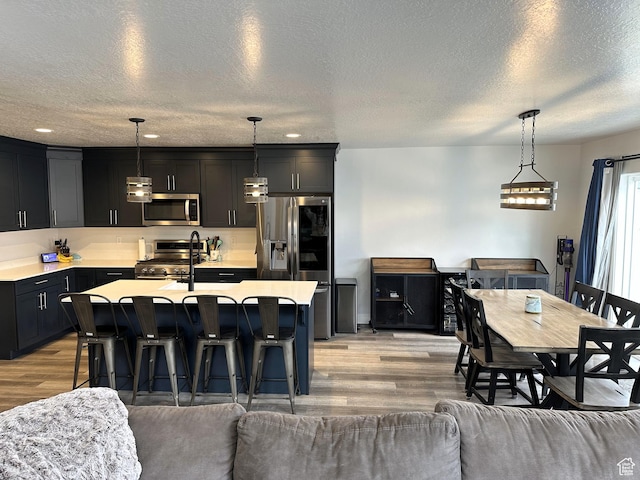 kitchen featuring stainless steel appliances, light wood-type flooring, open floor plan, light countertops, and a textured ceiling
