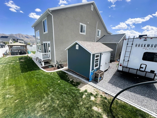 back of property with an outbuilding, a gazebo, a shed, stucco siding, and a mountain view