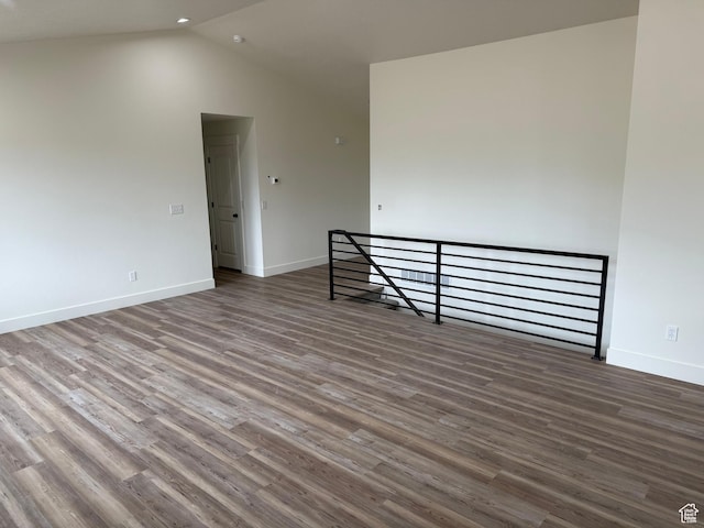 unfurnished room with vaulted ceiling, wood finished floors, and baseboards