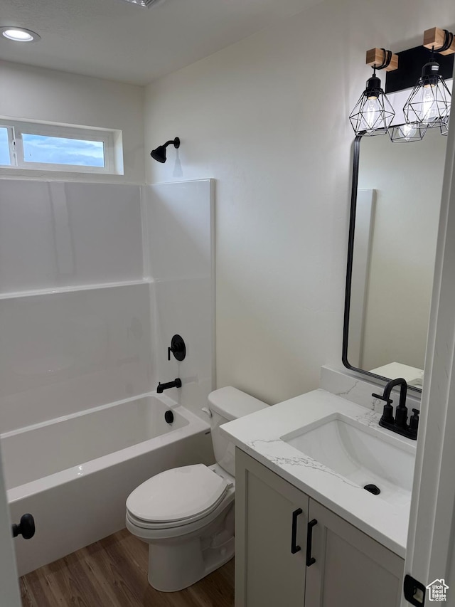 bathroom featuring wood finished floors, toilet, vanity, and bathtub / shower combination