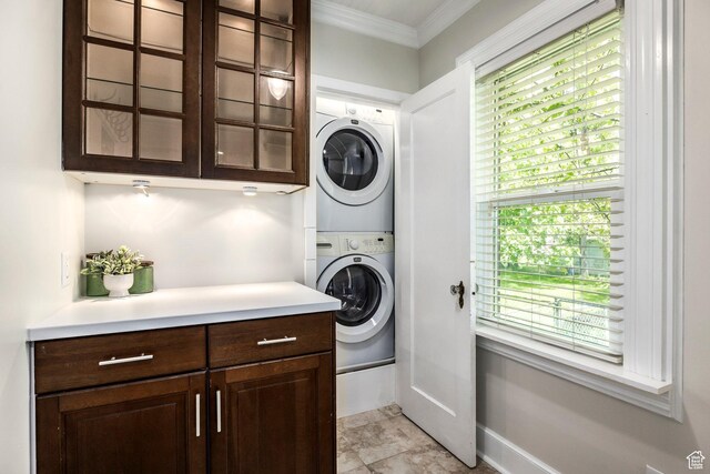 laundry room with stacked washer / drying machine, ornamental molding, and baseboards