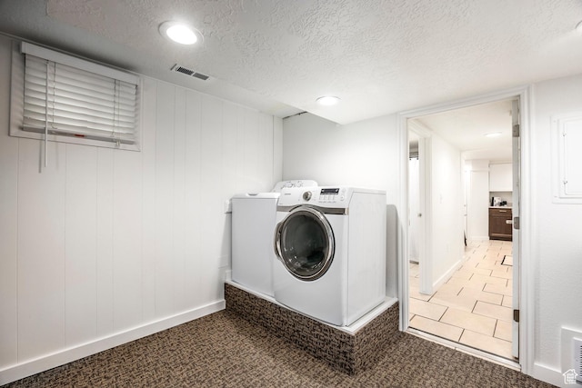 washroom featuring washer and clothes dryer, a textured ceiling, baseboards, and light carpet