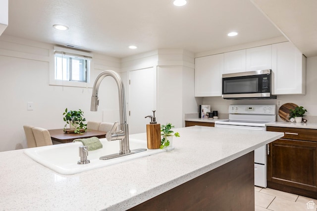 kitchen with stainless steel microwave, electric stove, white cabinets, a sink, and recessed lighting