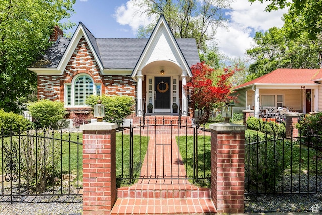 english style home featuring a fenced front yard, a gate, and brick siding