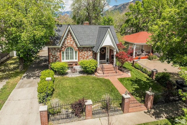 english style home featuring brick siding, a gate, a mountain view, and a chimney