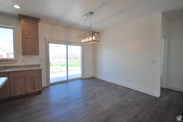 kitchen with dark wood-style flooring, brown cabinetry, baseboards, pendant lighting, and recessed lighting