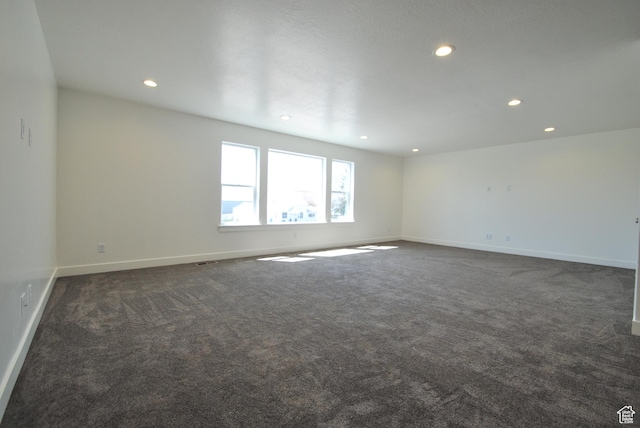 spare room with recessed lighting, dark carpet, and baseboards