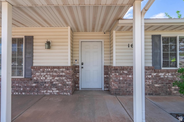 doorway to property with brick siding and a porch