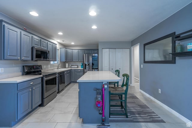 kitchen with appliances with stainless steel finishes, a breakfast bar, light countertops, a kitchen island, and recessed lighting