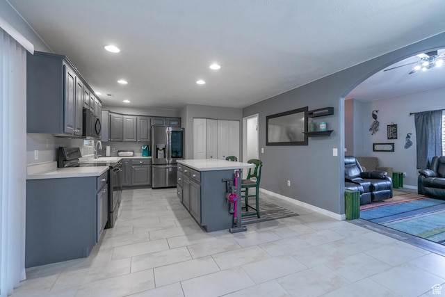 kitchen with stainless steel fridge with ice dispenser, black range with electric cooktop, gray cabinetry, arched walkways, and light countertops