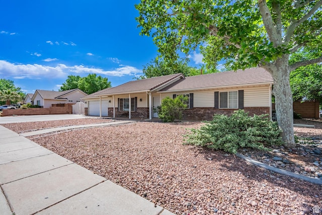 ranch-style home featuring brick siding, concrete driveway, an attached garage, a tile roof, and fence