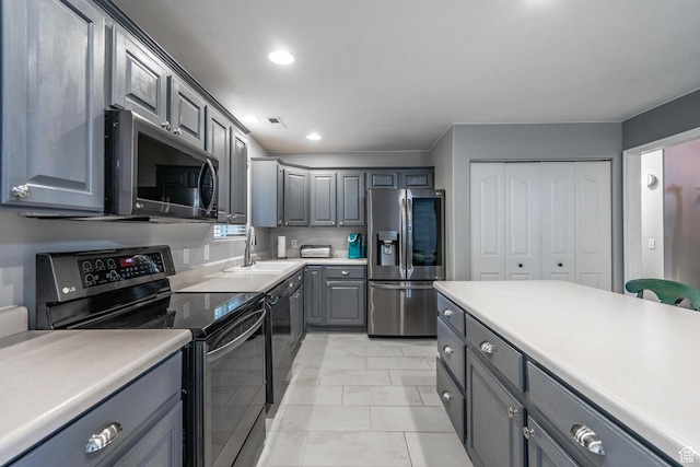 kitchen featuring appliances with stainless steel finishes, gray cabinets, a sink, recessed lighting, and light countertops
