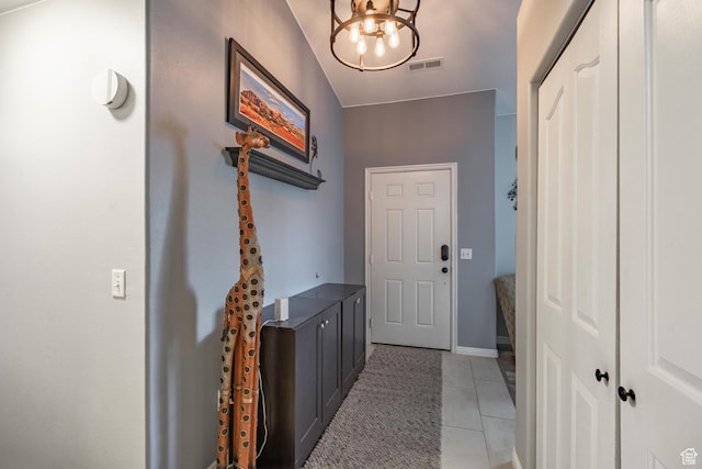 doorway with a chandelier, light tile patterned floors, and baseboards