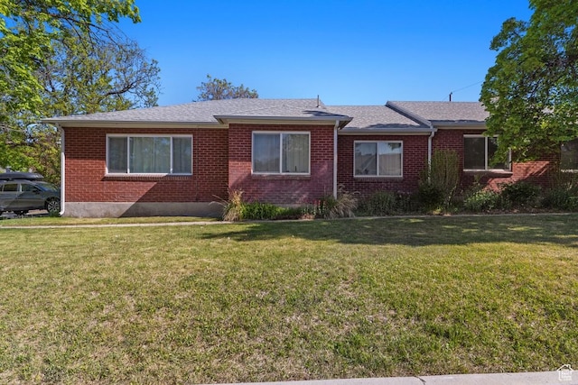 view of front of property with a front lawn, brick siding, and a shingled roof