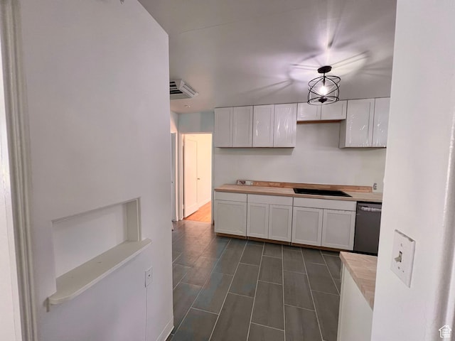 kitchen with dishwashing machine, white cabinetry, and a sink