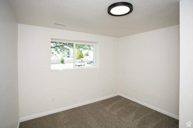 empty room featuring dark colored carpet and baseboards