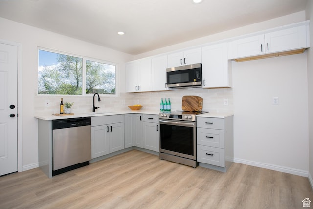kitchen with appliances with stainless steel finishes, light wood-style floors, decorative backsplash, and recessed lighting