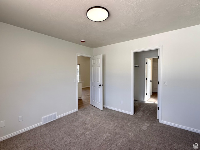 unfurnished bedroom featuring carpet, baseboards, and a textured ceiling