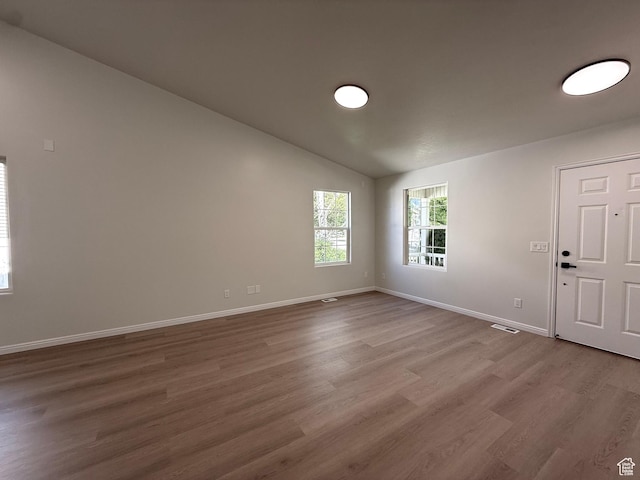 unfurnished room featuring wood finished floors, baseboards, and lofted ceiling