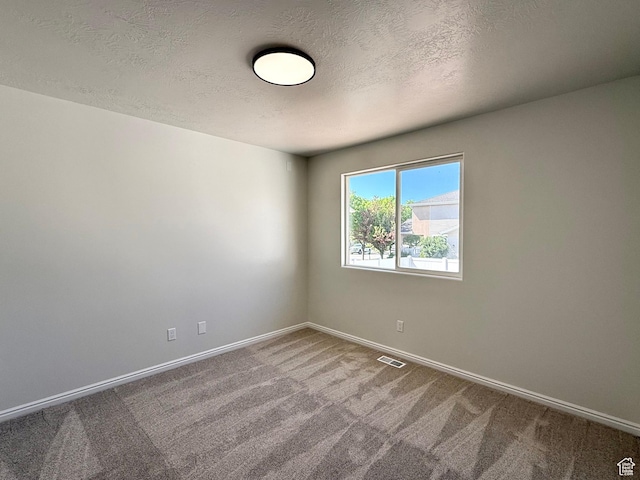spare room featuring carpet flooring, baseboards, and a textured ceiling