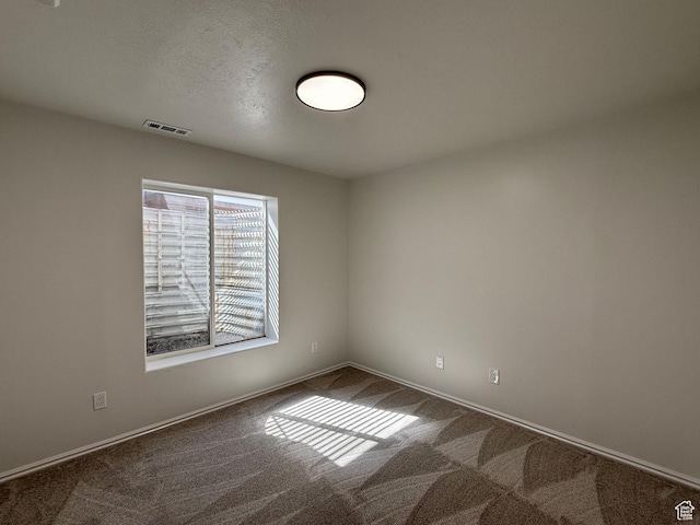 unfurnished room featuring dark colored carpet and baseboards