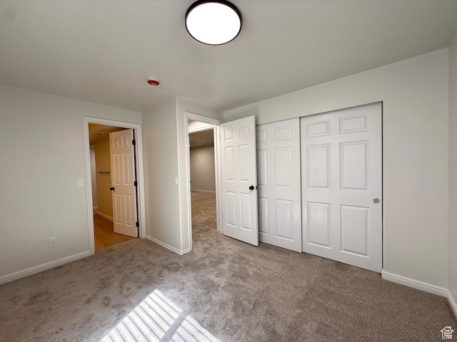 unfurnished bedroom featuring carpet floors, baseboards, and a closet