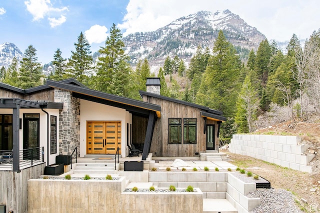 9335 N Canopy Ln E, Sundance, UT 84604 - view of front facade with a chimney, a mountain view, stone siding, and fence