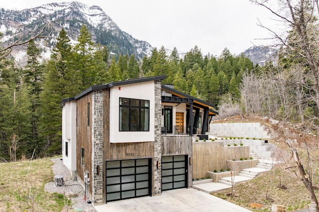 9335 N Canopy Ln E, Sundance, UT 84604 - view of outbuilding with a mountain view, stairs, concrete driveway, a garage, and a forest view