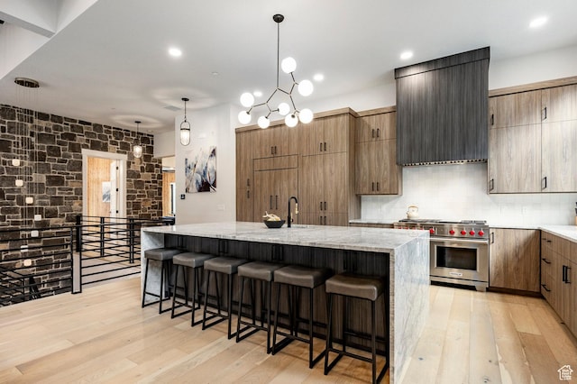 9335 N Canopy Ln E, Sundance, UT 84604 - kitchen featuring luxury range, light wood-type flooring, a breakfast bar, an island with sink, and recessed lighting