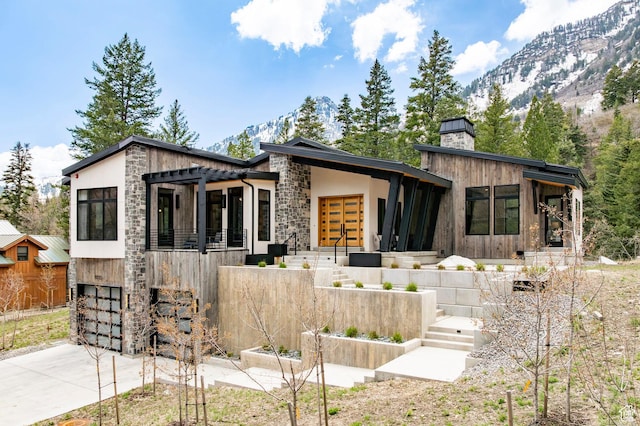 9335 N Canopy Ln E, Sundance, UT 84604 - contemporary home with stone siding, a garage, concrete driveway, a chimney, and a mountain view