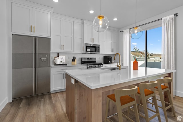 101 N 950 E Unit 36, Tremonton, UT 84337 - kitchen with a sink, appliances with stainless steel finishes, light wood-style floors, backsplash, and a kitchen island with sink