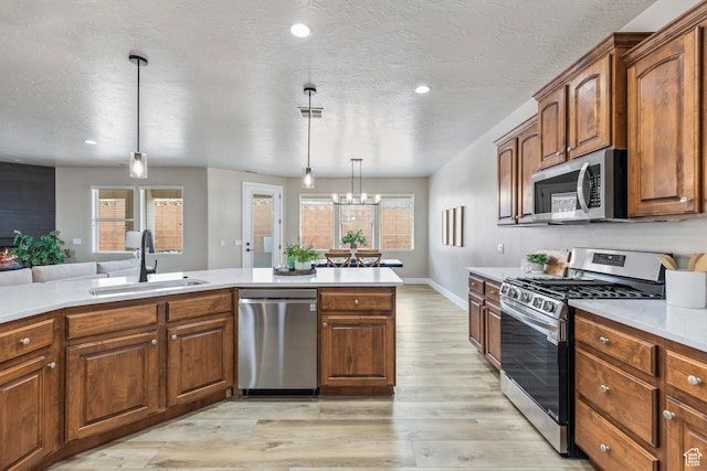1095 S White Sands Dr, Washington, UT 84780 - kitchen with stainless steel appliances, a sink, light wood-style flooring, light countertops, and plenty of natural light
