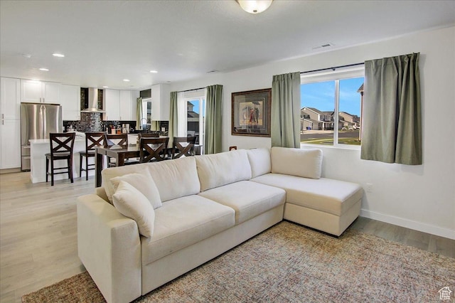 living area featuring baseboards, light wood-style floors, and recessed lighting