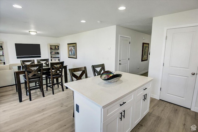 kitchen featuring light wood finished floors, a center island, white cabinets, open floor plan, and recessed lighting