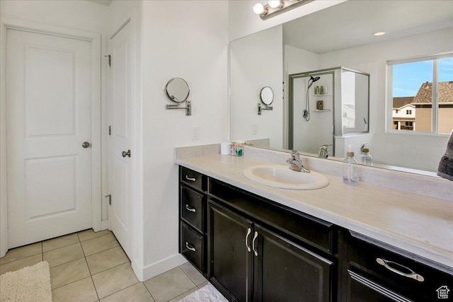 bathroom with tile patterned floors, vanity, a stall shower, and baseboards